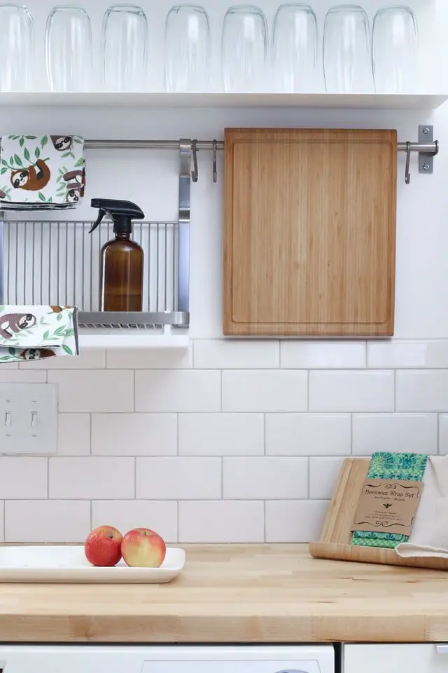 Clean looking kitchen with apples and cutting board.