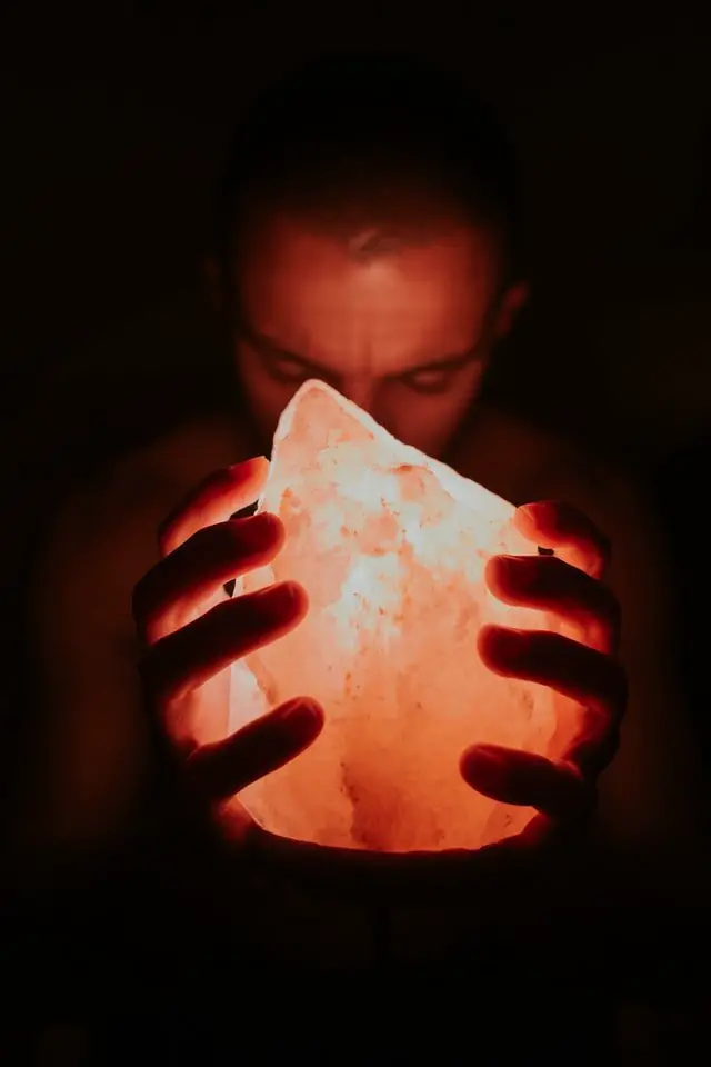 A person holding a bright glowing salt lamp.
