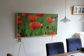 An infrared heater with a pciture of red flowers mounted horziontally on the wall.